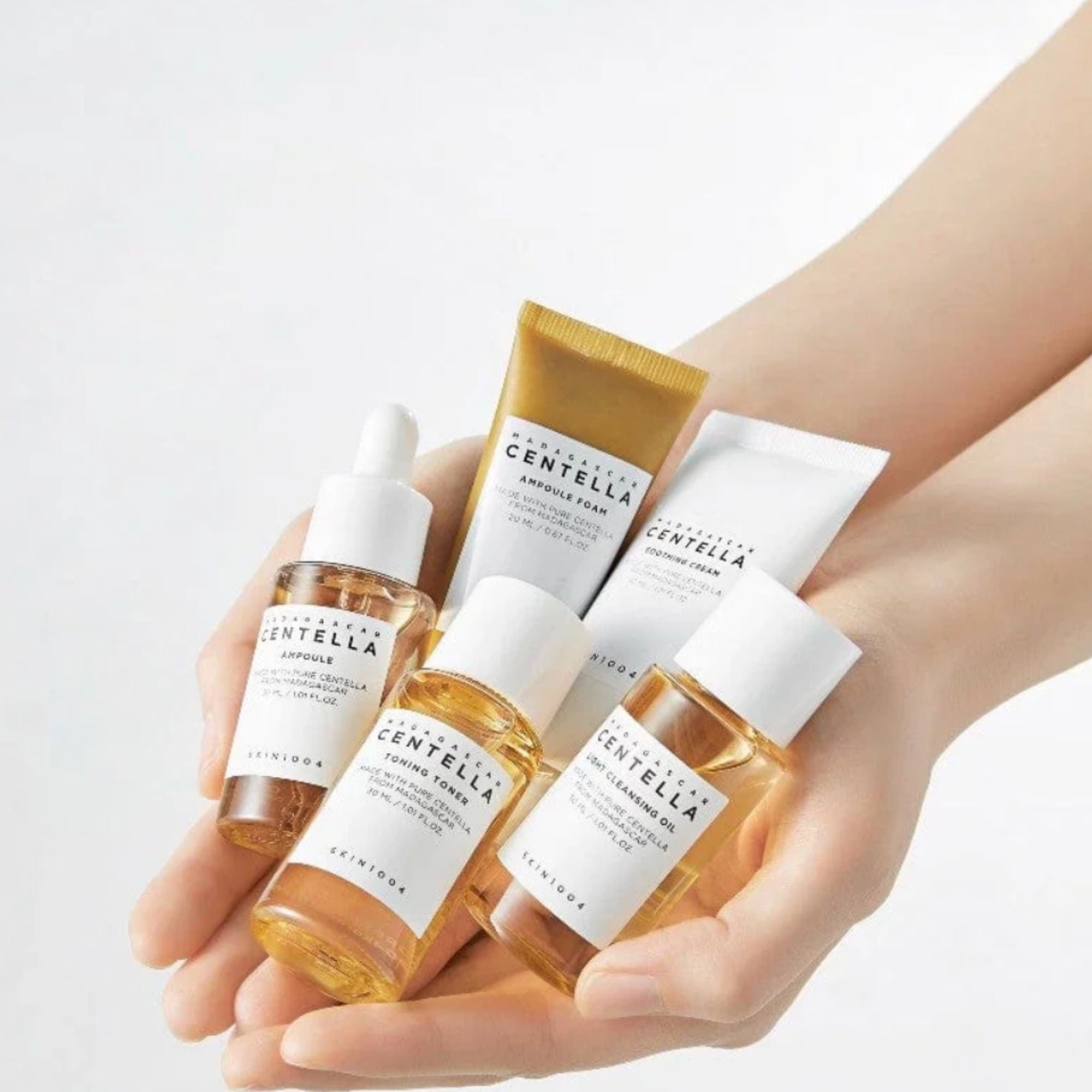 Hand holding Centella Asiatica skincare products on a light background