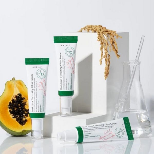 Skincare products with a papaya and a vase on a light background