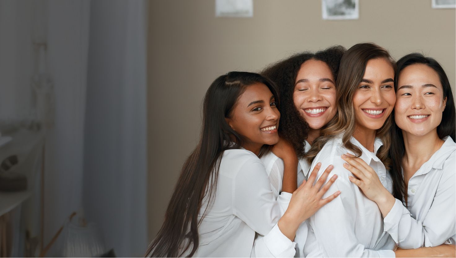 Four women in white shirts posing together in a bathroom.
